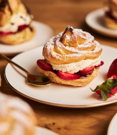 Closeup shot of delicious cream puff with strawberries on a wooden table