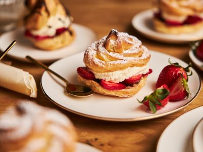 Closeup shot of delicious cream puff with strawberries on a wooden table